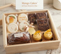 Mango Cakes Artisan Desserts Box with signature cookies, fudge brownies, mini banana bread, and cupcakes in a wooden crate